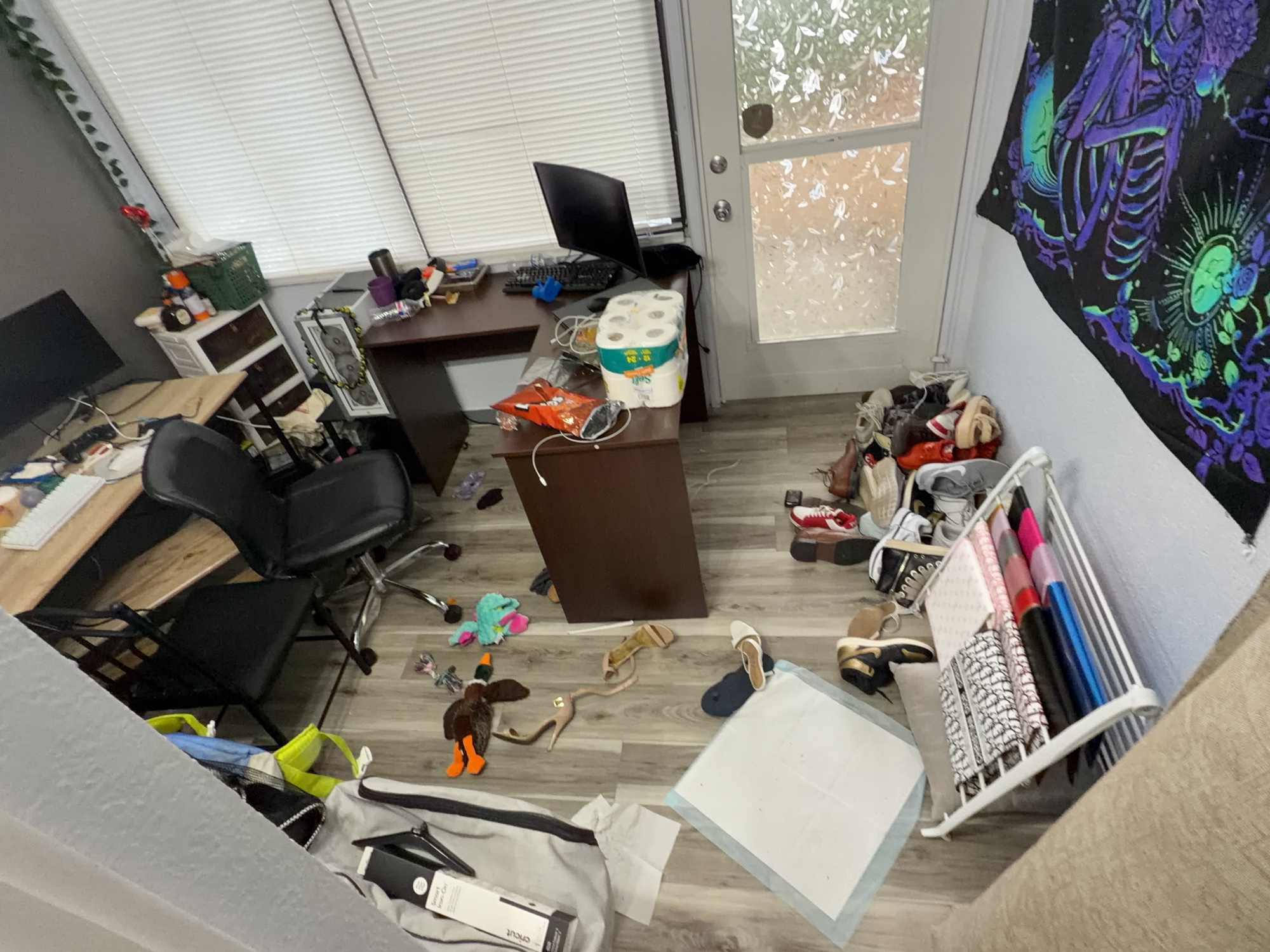 Home office with loose items across the floor and desks before cleaning and tidying.