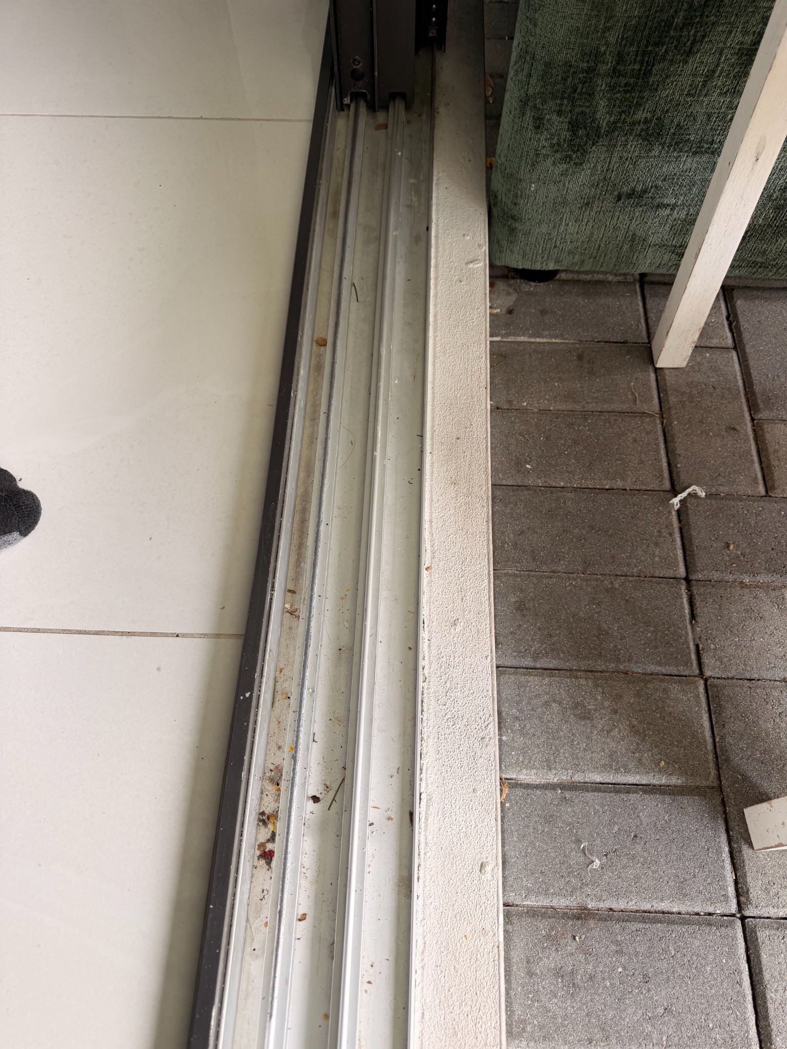Sliding-door track with sand and loose debris before cleaning.